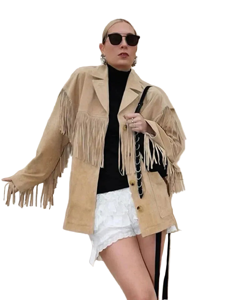 Veste à franges pour femme, modèle Charlène. Veste beige en suède avec franges élégantes sur les manches, portée avec un t-shirt noir et des shorts blancs. Un look chic et moderne, accessoirisé avec un sac à main noir. Parfait pour un style décontracté et tendance.