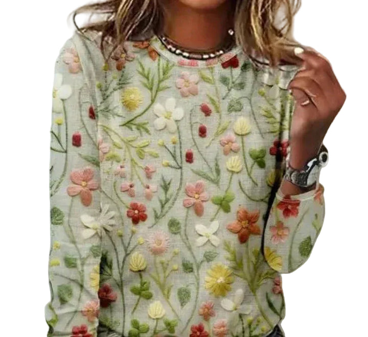 Pull printanier à col rond avec motifs floraux colorés et détails en relief, manches longues, porté avec accessoires.