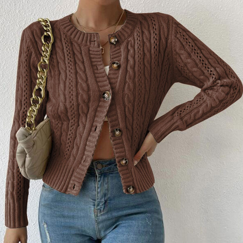 Femme portant un cardigan en maille torsadée marron, légèrement ouvert sur un haut clair, assorti à un jean taille haute et accompagné d’un sac à chaîne dorée.