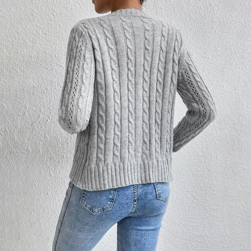 Vue arrière d’un cardigan en maille torsadée gris clair porté par une femme, montrant les détails des motifs en tricot et les bords côtelés, assorti à un jean bleu clair ajusté.