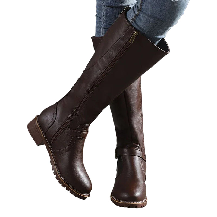 Paire de bottes hautes en cuir synthétique marron foncé, dotées d’une fermeture éclair latérale discrète et d’une bride décorative avec boucle au niveau de la cheville. Leur semelle crantée et leur talon bas assurent confort et stabilité. Ces bottes élégantes au style classique sont parfaites pour l’automne et l’hiver, faciles à assortir avec un jean ou une robe pour un look chic et décontracté.