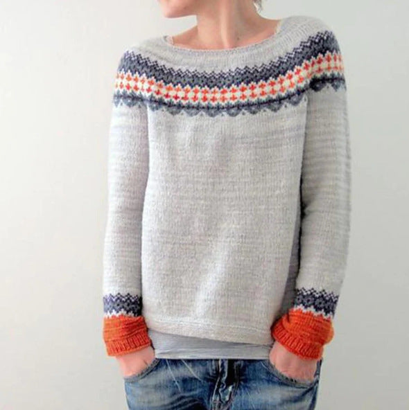 Un pull vintage pour femme, de couleur grise avec des motifs colorés en haut et aux poignets. Le modèle présente des touches de rouge, bleu et orange, avec un col rond et des manches longues. Ce pull allie confort et style, parfait pour apporter une touche chaleureuse et originale à votre look hivernal.