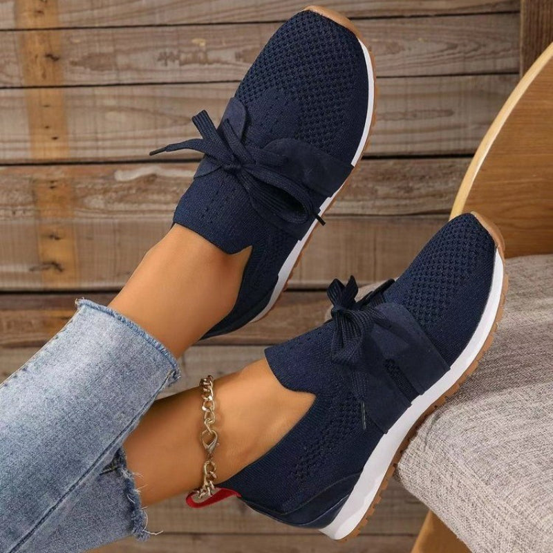 Modernes, sneakers bleu marine en maille avec bande et lacets, semelle blanche et gomme, portées avec un jean en intérieur.