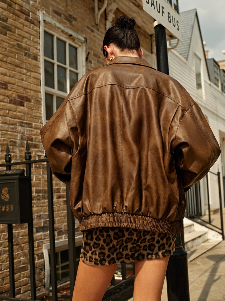 Vue arrière de cette veste en cuir marron au style oversized, avec une taille élastiquée pour un ajustement confortable. Associez-la à une jupe léopard pour un look moderne et élégant, parfait pour les journées décontractées.