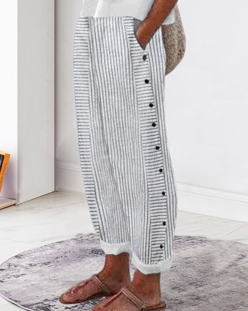 Jogging décontracté femme à rayures gris et blanc, coupe ample avec taille élastique, poches et boutons décoratifs sur le côté, porté avec des chaussures plates style moderne et confortable.