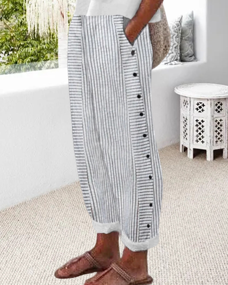 Jogging décontracté femme rayé gris et blanc, coupe ample avec taille élastique, poches et boutons sur le côté, ourlets retroussés, porté avec des mocassins  look moderne et confortable.
