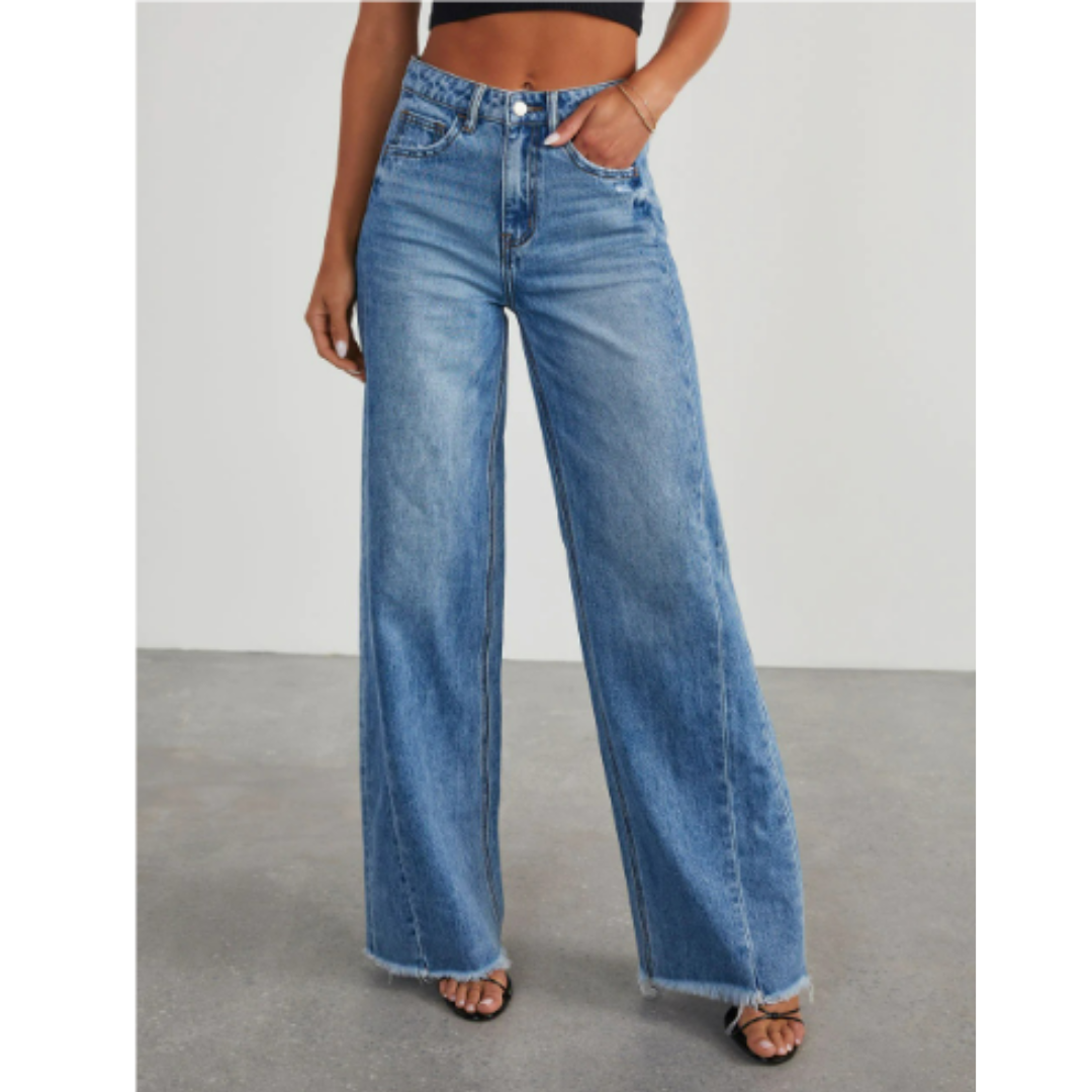 Pantalon taille haute femme Dorothée tendance, coupe évasée en jean bleu clair, avec bas effiloché, porté avec un crop top noir et des sandales à talons.