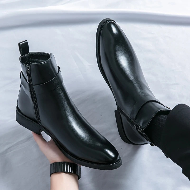 Bottines Chelsea noires en cuir lisse avec fermeture éclair latérale, bout arrondi et petit talon, présentées sur fond clair.