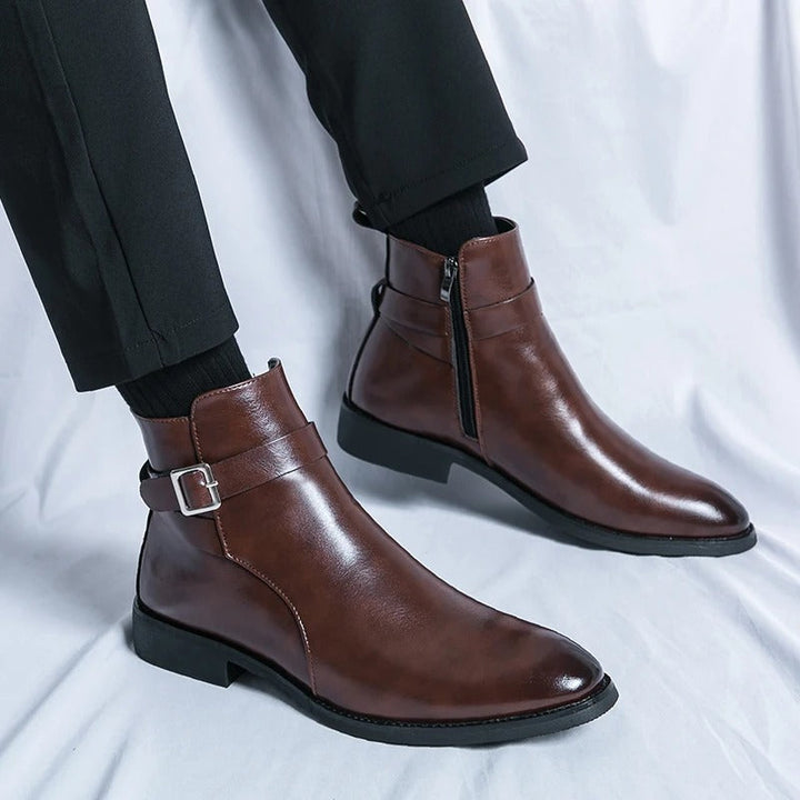 Bottines cheville marron en cuir lisse, portées avec un pantalon noir, fermeture éclair latérale et bride arrière avec boucle, semelle basse.