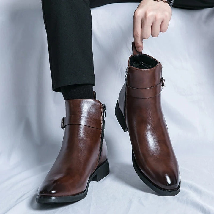 Bottines cheville marron en cuir lisse portées avec un pantalon noir, bout légèrement effilé, fermeture éclair latérale et bride avec boucle.