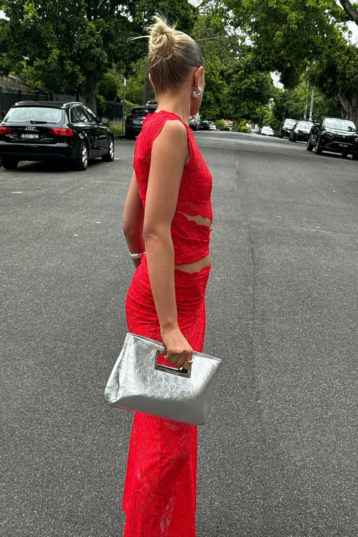 Cet ensemble élégant se compose d'un top court en dentelle rouge et d'une jupe sirène ajustée, parfaitement assortie à un sac à main argenté. Idéal pour un événement chic ou une soirée spéciale, il met en valeur la silhouette avec une allure raffinée et moderne.