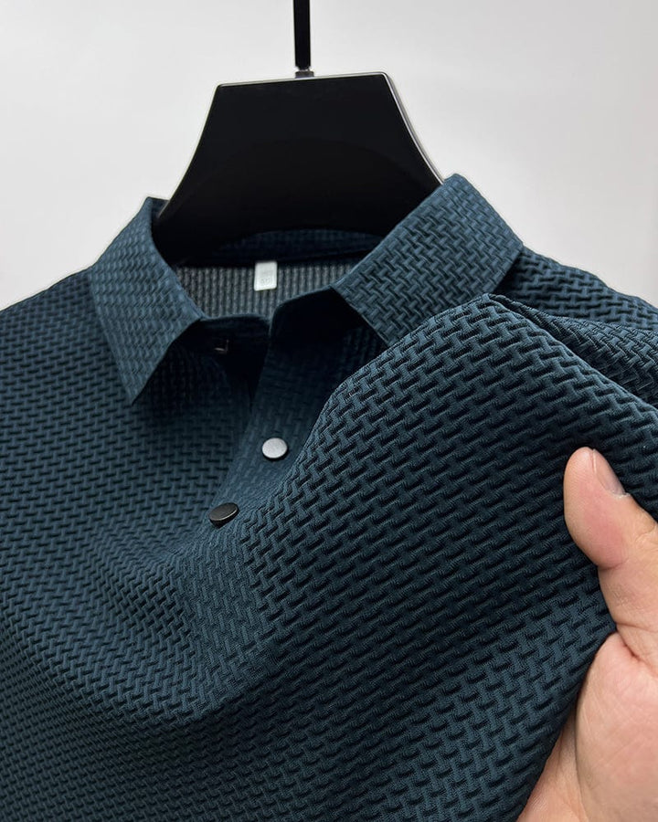 Gros plan sur un polo bleu foncé en maille texturée, avec un col classique et des boutons noirs contrastés. Ce polo allie confort et style moderne, parfait pour un look décontracté et élégant.
