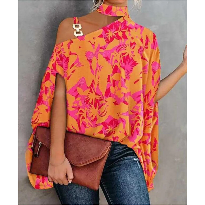 top asymétrique à une épaule, orné de motifs floraux vibrants en rose et orange, avec un détail en chaîne dorée à l'épaule, parfait pour un look tendance et élégant, à associer avec un jean.
