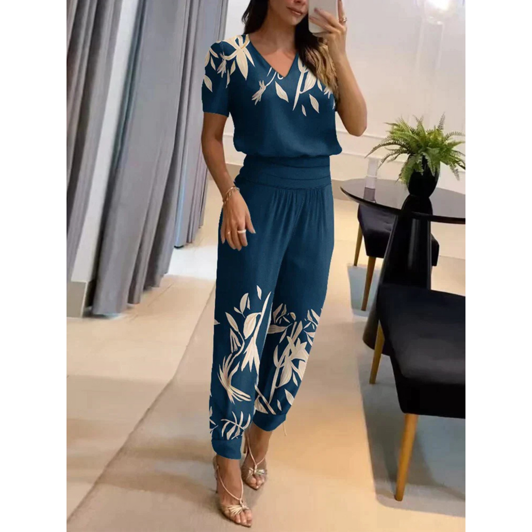 Ensemble chic pour femme Eugénie, moderne et élégant, de couleur bleu foncé avec des motifs floraux blancs. Ce set fluide, composé d'un haut à col en V et d'un pantalon assorti à bords côtelés, offre un look raffiné et décontracté, idéal pour une sortie stylée.