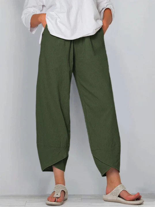 Pantalon palazzo pour femme vert foncé, taille haute et coupe large en tissu léger, avec poches latérales, porté avec une chemise blanche et des sandales pour un style naturel, confortable et moderne.