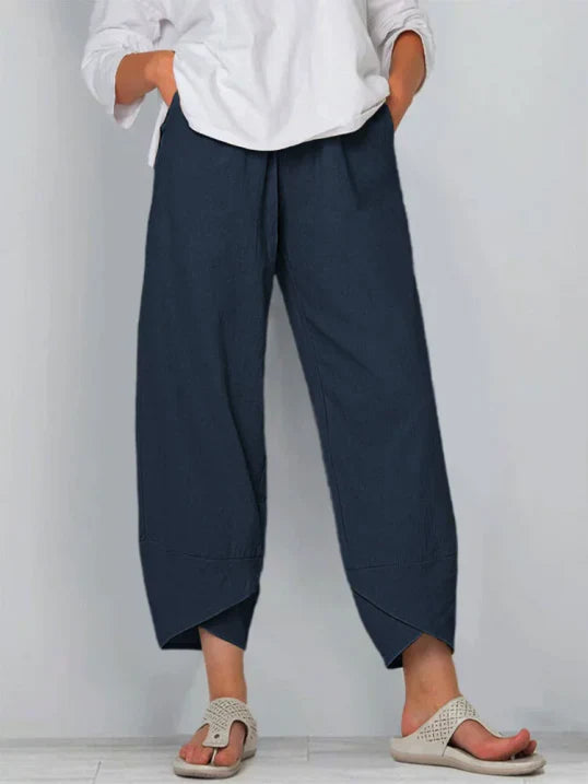 Pantalon palazzo pour femme bleu foncé, taille haute et coupe large en tissu léger, avec poches latérales, porté avec une chemise blanche et des sandales pour un style élégant, confortable et moderne.