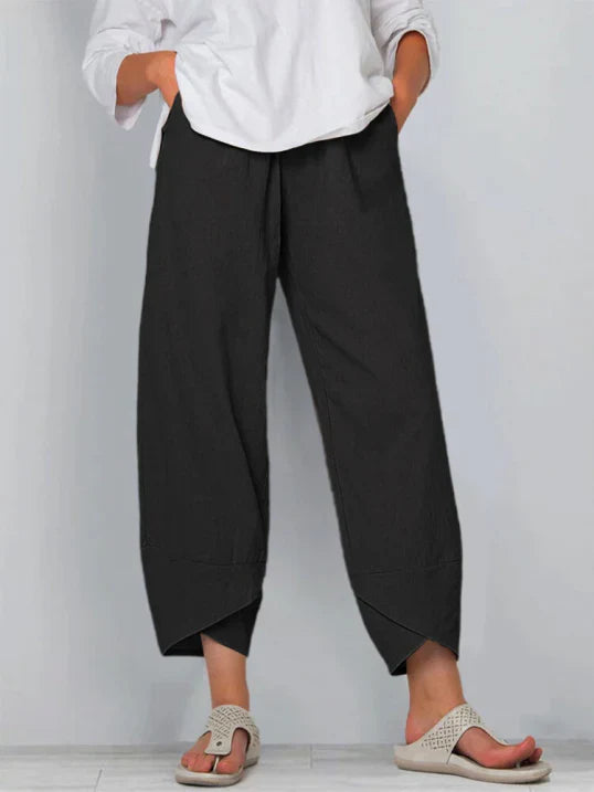 Pantalon palazzo pour femme noir, taille haute et coupe large en tissu léger, avec poches latérales, porté avec une chemise blanche et des sandales pour un style sobre, confortable et moderne.
