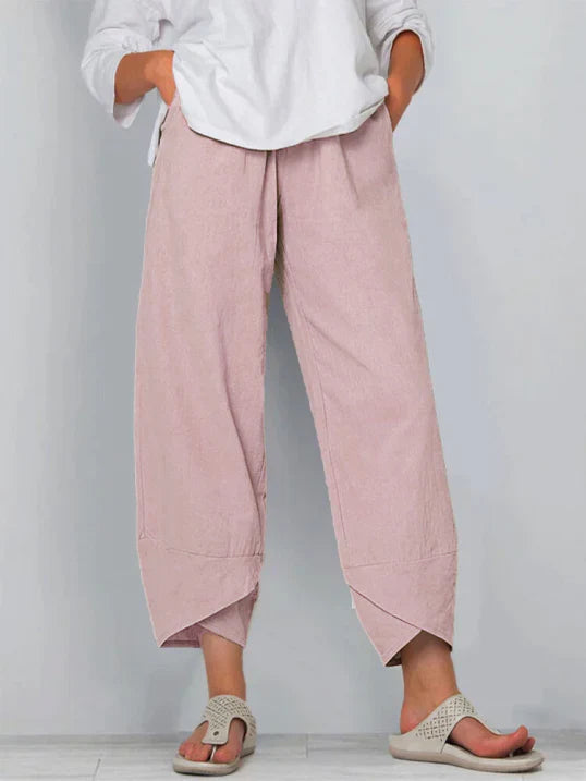 Pantalon palazzo pour femme rose poudré, taille haute et coupe large en tissu léger, avec poches latérales, porté avec une chemise blanche et des sandales pour un style doux, élégant et moderne.