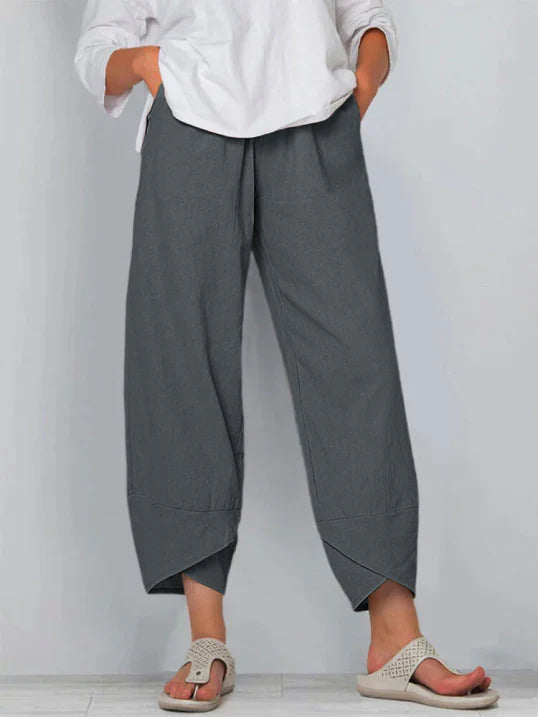 Pantalon palazzo pour femme gris foncé, taille haute et coupe large en tissu léger, avec poches latérales, porté avec une chemise blanche et des sandales pour un style confortable, élégant et moderne.