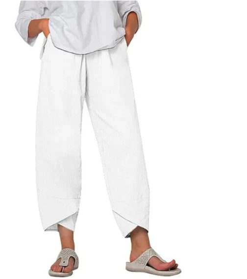 Pantalon palazzo pour femme blanc, taille haute et coupe large en tissu léger, avec poches latérales, porté avec une chemise blanche et des sandales pour un style épuré, frais et élégant.
