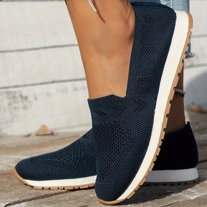 Chaussure d’été femme Fantine tendance bleu marine, slip-on en maille respirante, bout arrondi et semelle épaisse blanche avec dessous cranté, vue de profil portée en extérieur.