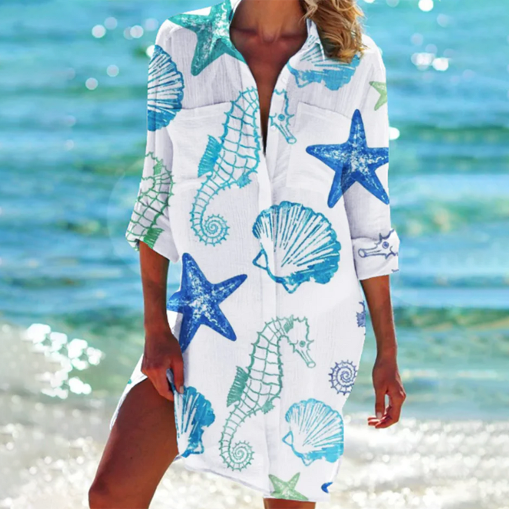 robe-chemise légère blanche à manches 3/4 avec col ouvert, imprimé marin étoiles de mer, coquillages et hippocampes bleus et verts, coupe fluide idéale pour un look estival en bord de mer.
