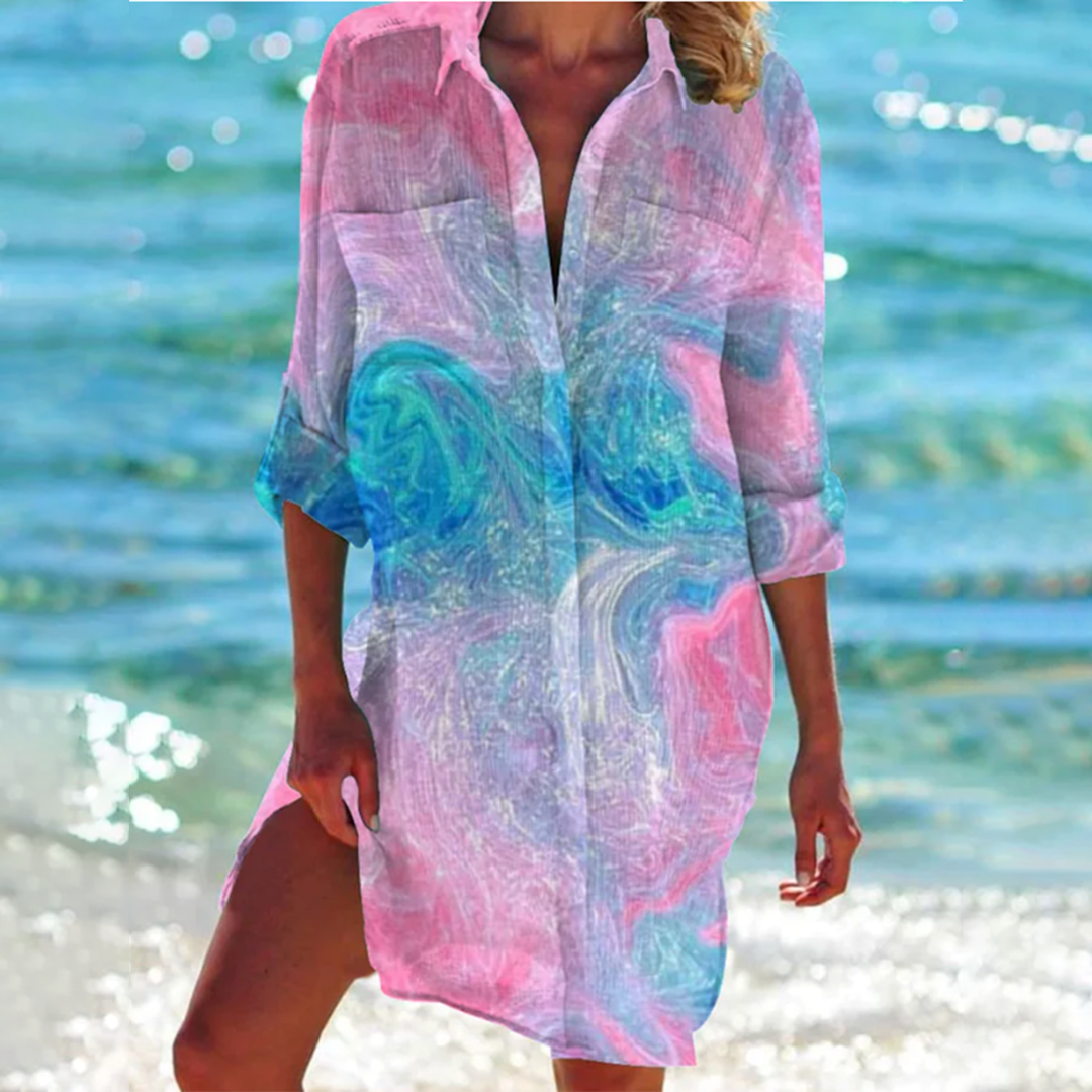 robe-chemise légère à manches 3/4 avec col ouvert, imprimé marbré aux nuances de rose et bleu, parfaite pour un look estival élégant et raffiné en bord de mer.