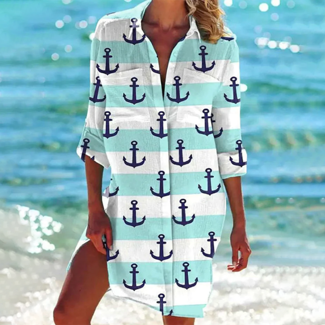 robe-chemise légère à manches 3/4 avec col ouvert, imprimé marin avec des ancres bleues sur fond bleu clair et blanc, parfaite pour un look nautique et estival en bord de mer.