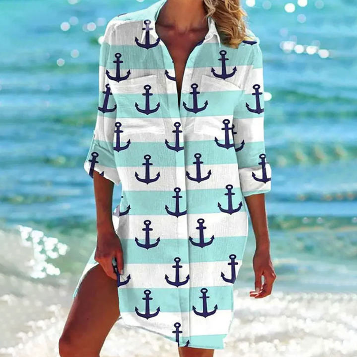 robe-chemise légère à manches 3/4 avec col ouvert, imprimé marin avec des ancres bleues sur fond bleu clair et blanc, parfaite pour un look nautique et estival en bord de mer.