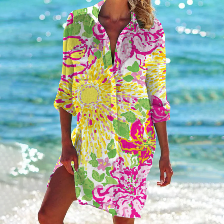 robe-chemise légère à manches 3/4 avec col ouvert, imprimé floral éclatant aux teintes de jaune, rose et vert, parfait pour un look estival lumineux et dynamique en bord de mer.