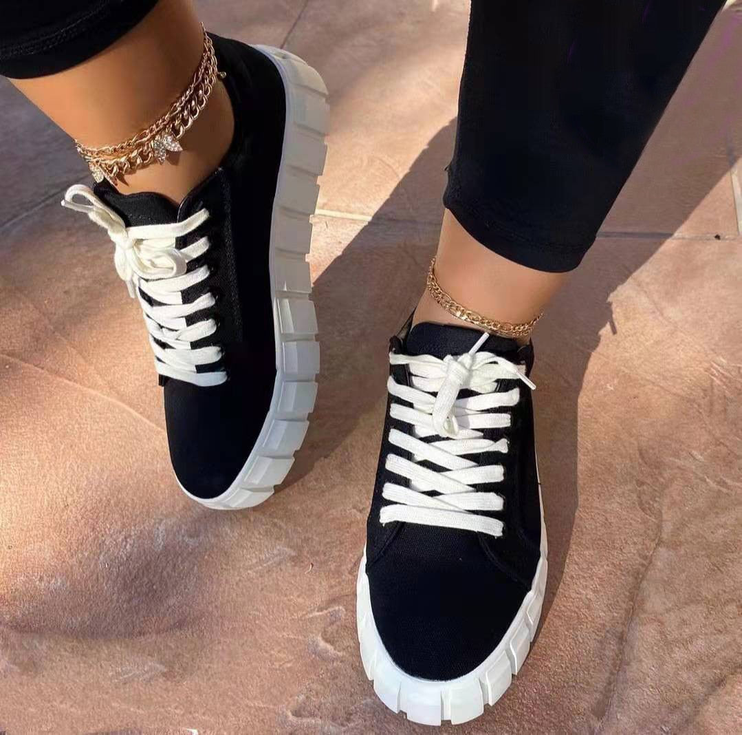 Baskets montantes femme Flavie tendance, sneakers noires avec lacets blancs et semelle épaisse blanche crantée, portées avec legging noir sur sol en pierre.