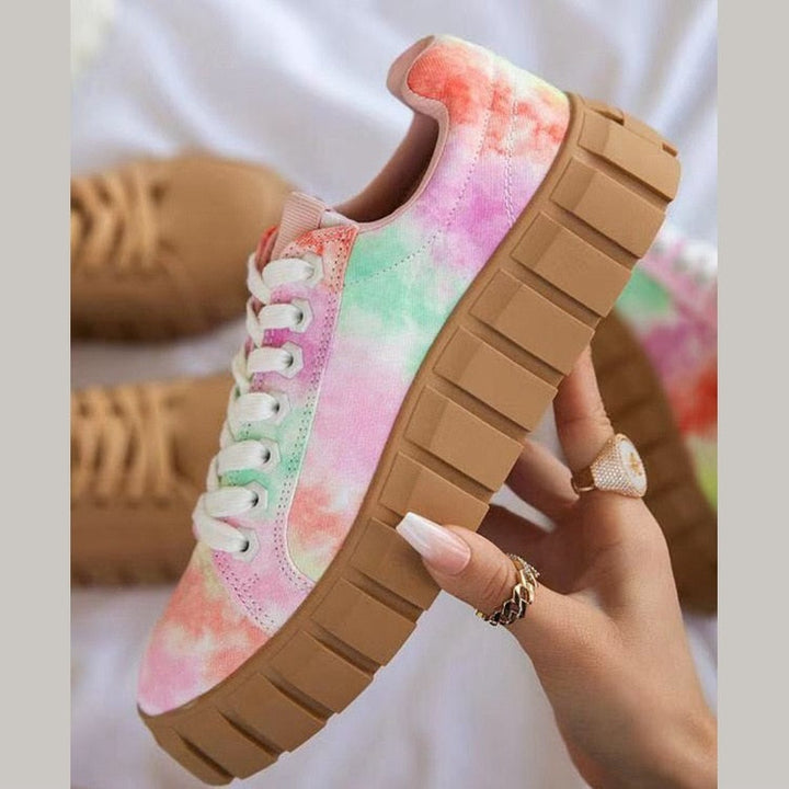 Baskets montantes femme Flavie tendance, sneaker multicolore effet tie-dye rose et vert avec lacets blancs et semelle épaisse beige crantée, tenue en main sur fond blanc.