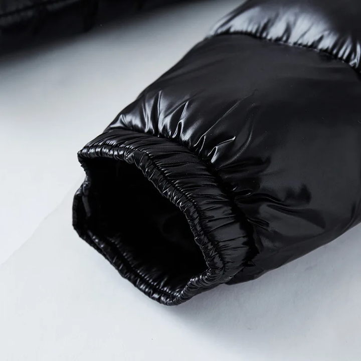 Vue rapprochée de la manche d'une doudoune noire brillante, mettant en évidence le tissu matelassé et l'élastique au niveau du poignet pour un ajustement confortable et isolant.