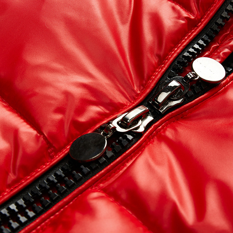 Détail de la fermeture éclair d'une doudoune rouge, avec des tirettes métalliques brillantes et une finition lisse sur le tissu matelassé pour un look moderne et pratique.