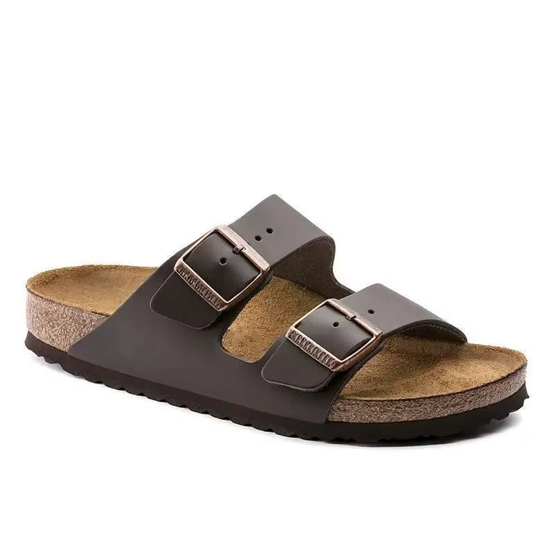 Sandales d'été pour femme, dotées de deux larges brides en cuir marron et de boucles métalliques réglables. La semelle intérieure en liège naturel épouse la forme du pied, offrant un confort et un maintien exceptionnels. La semelle extérieure antidérapante assure une démarche stable, idéale pour les journées chaudes et une tenue décontractée.