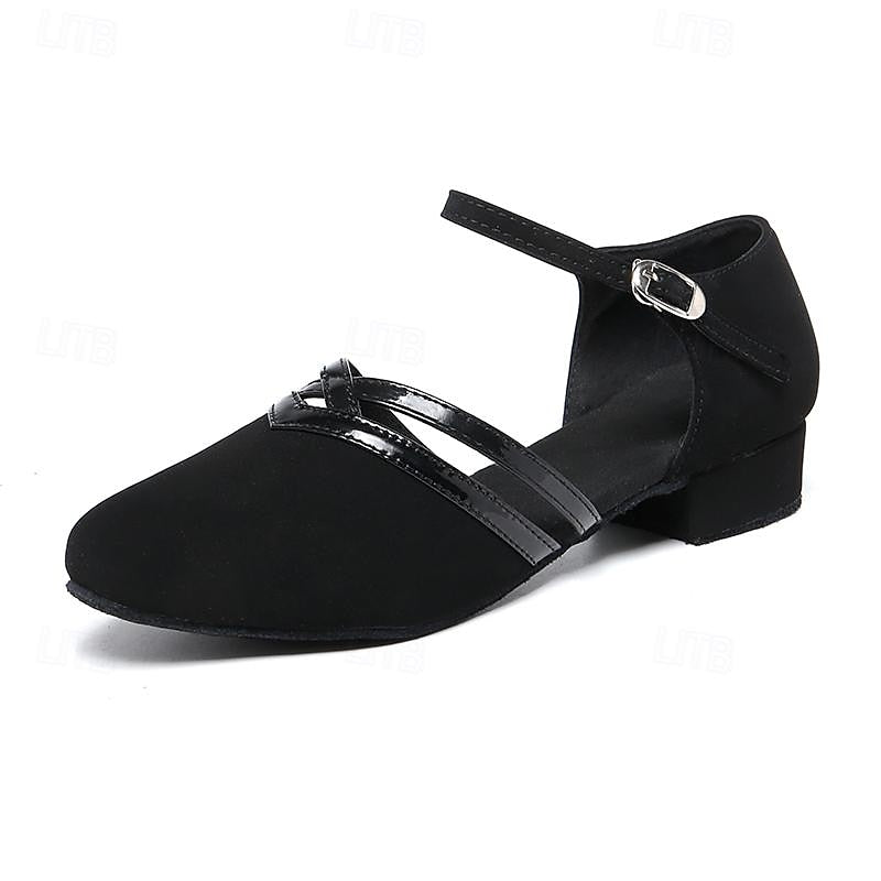 Chaussure de danse pour femme noire, modèle moderne à bout fermé avec brides croisées vernies et sangle réglable à boucle, talon bas, sur fond blanc.
