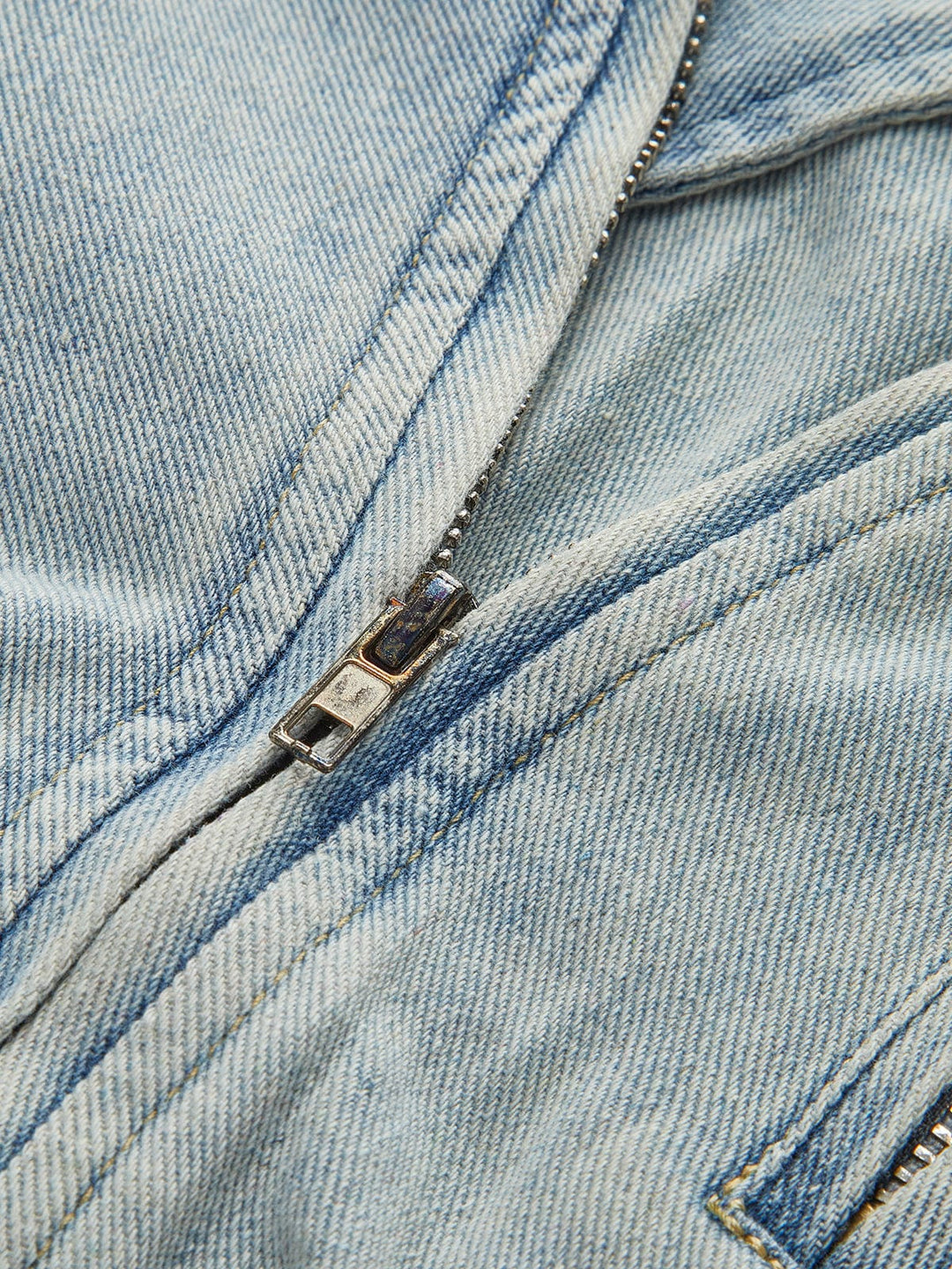 Détail de la fermeture éclair métallique de la veste, soulignant les finitions soignées et le design moderne. Ce détail pratique et stylé ajoute une touche supplémentaire à cette veste en denim idéale pour l'hiver