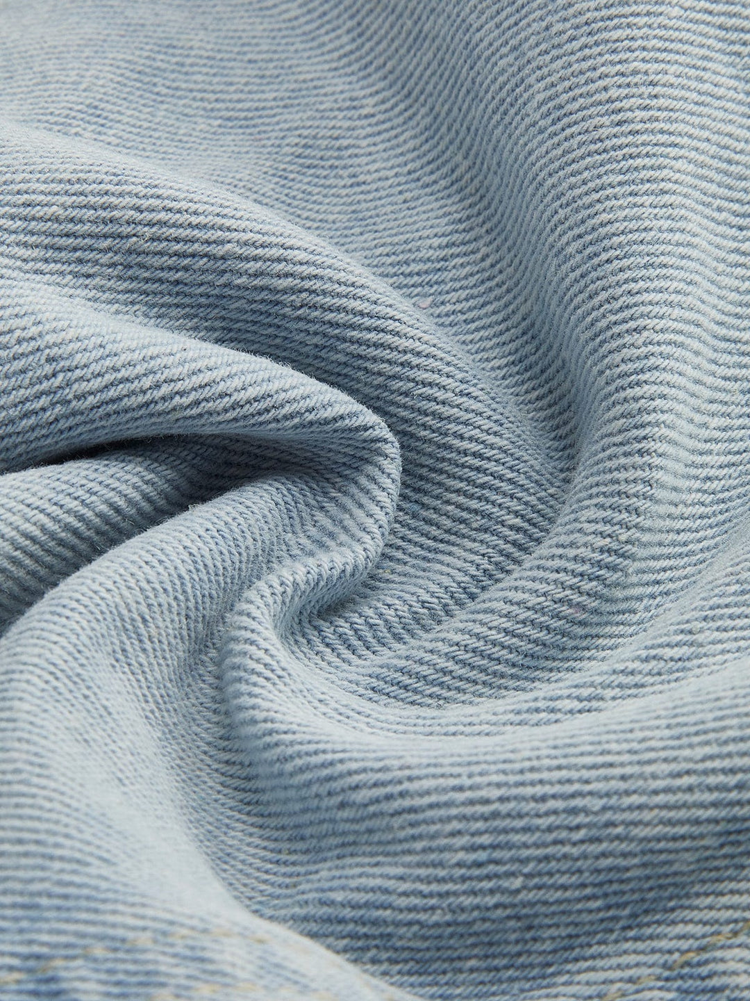 Zoom sur le tissu en denim bleu clair de la veste en jean courte Giselle. Ce denim de qualité, doux au toucher et légèrement texturé, offre une finition soignée. Il est idéal pour une coupe moderne et décontractée, apportant confort et style à votre tenue.