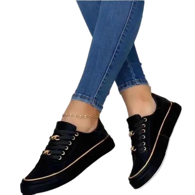 Femme portant les baskets plateforme Guenièvre noires, style moderne avec lacets et détails dorés, semelle épaisse confortable, associées à un jean slim pour un look urbain chic.
