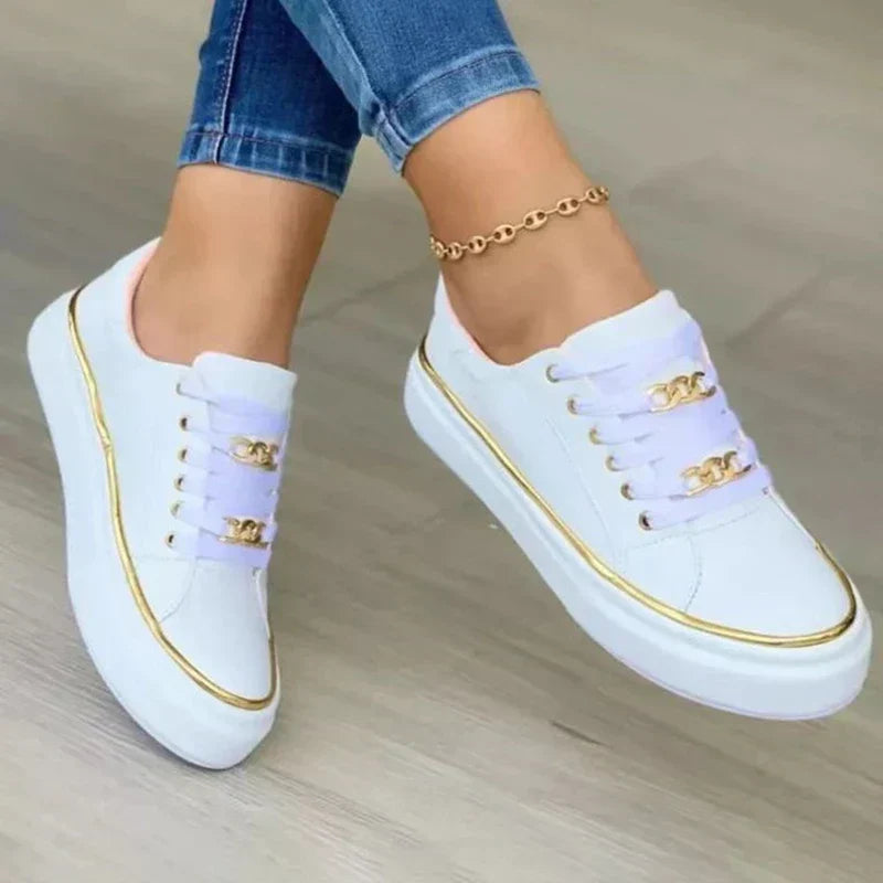 Gros plan des baskets plateforme Guenièvre blanches, style moderne avec fin liseré doré et détails chaîne dorée sur les lacets, semelle épaisse confortable pour un look élégant.