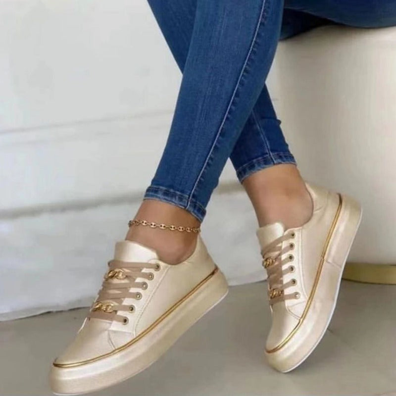 Femme portant les baskets plateforme Guenièvre beige crème, design moderne avec lacets et détails dorés, semelle épaisse confortable, associées à un jean slim pour un look casual chic.