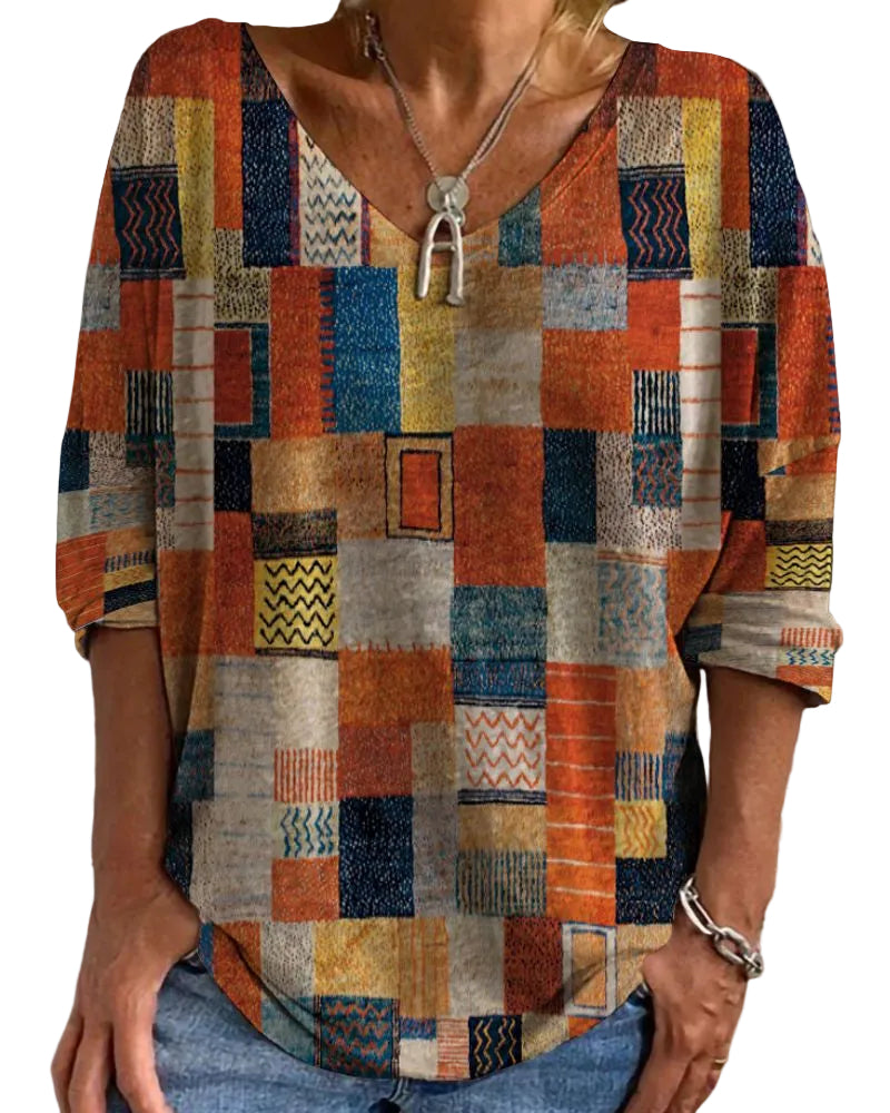 Haut d'été femme Gwladys à manches longues, style tendance avec imprimé géométrique aux couleurs vives (orange, bleu, jaune), porté avec un collier, sur fond extérieur.