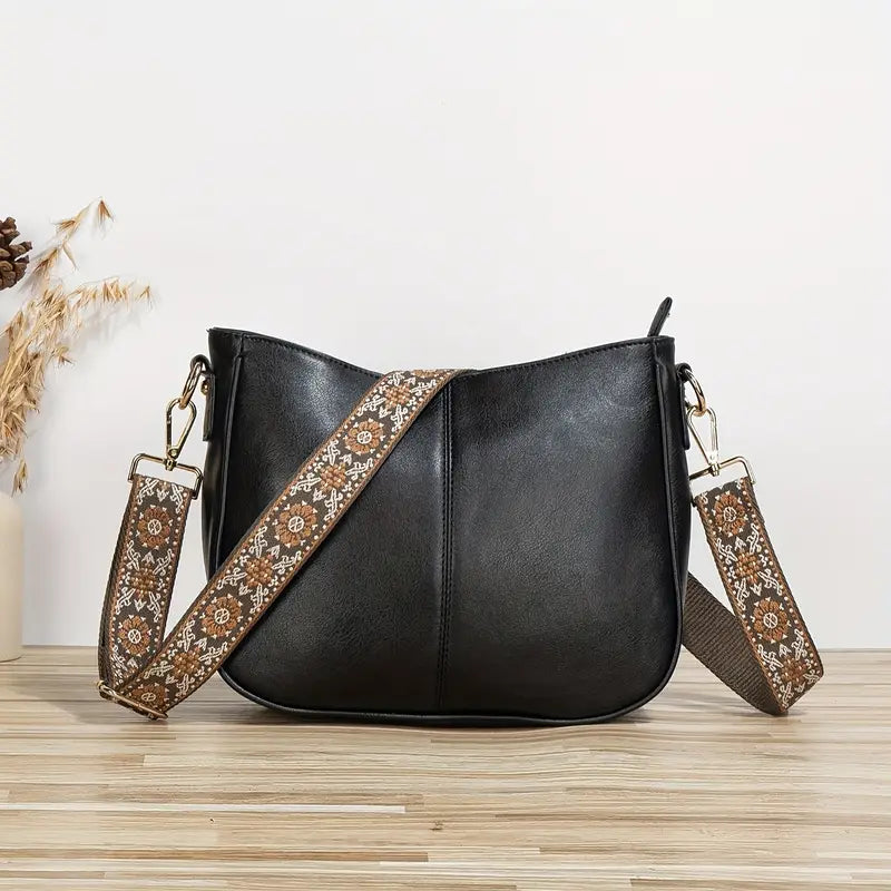 Sac bandoulière tendance Hermine pour femme en simili cuir noir, format besace avec fermeture zippée, coutures centrales et large sangle réglable à motif ethnique, présenté sur fond clair.
