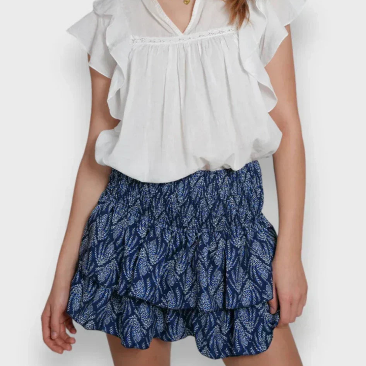 Jupe mini pour femme Jalyssa, modèle moderne avec un motif bleu élégant et des volants fluides. Dotée d'une taille élastique, elle offre un ajustement confortable et un look féminin et léger, parfait pour l'été.