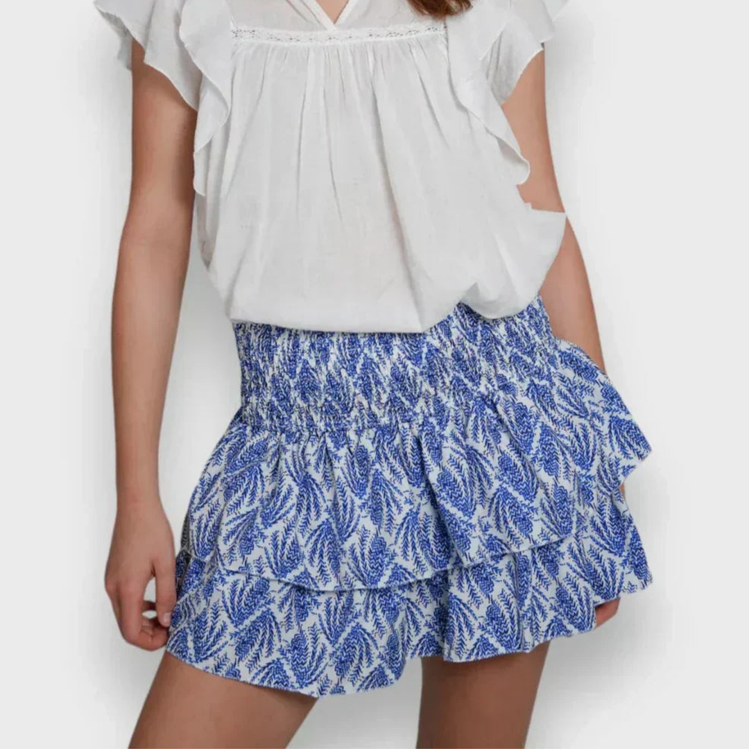Jupe mini pour femme Jalyssa, modèle moderne avec un motif floral bleu et blanc. Elle présente un design à volants superposés et une taille élastique pour un confort optimal. Parfaite pour un look estival chic et décontracté.