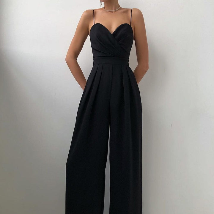 Une combinaison noire sans manches avec un décolleté croisé et un pantalon large, offrant un look élégant et moderne.