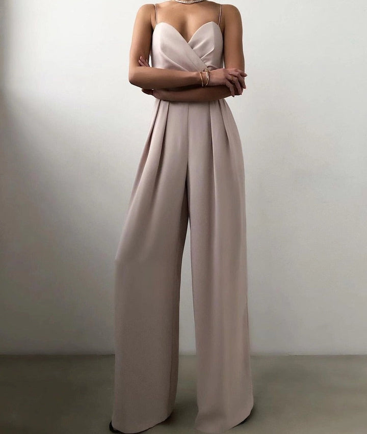 Une combinaison sans manches de couleur beige avec un décolleté croisé et un pantalon large, créant un look élégant et moderne.