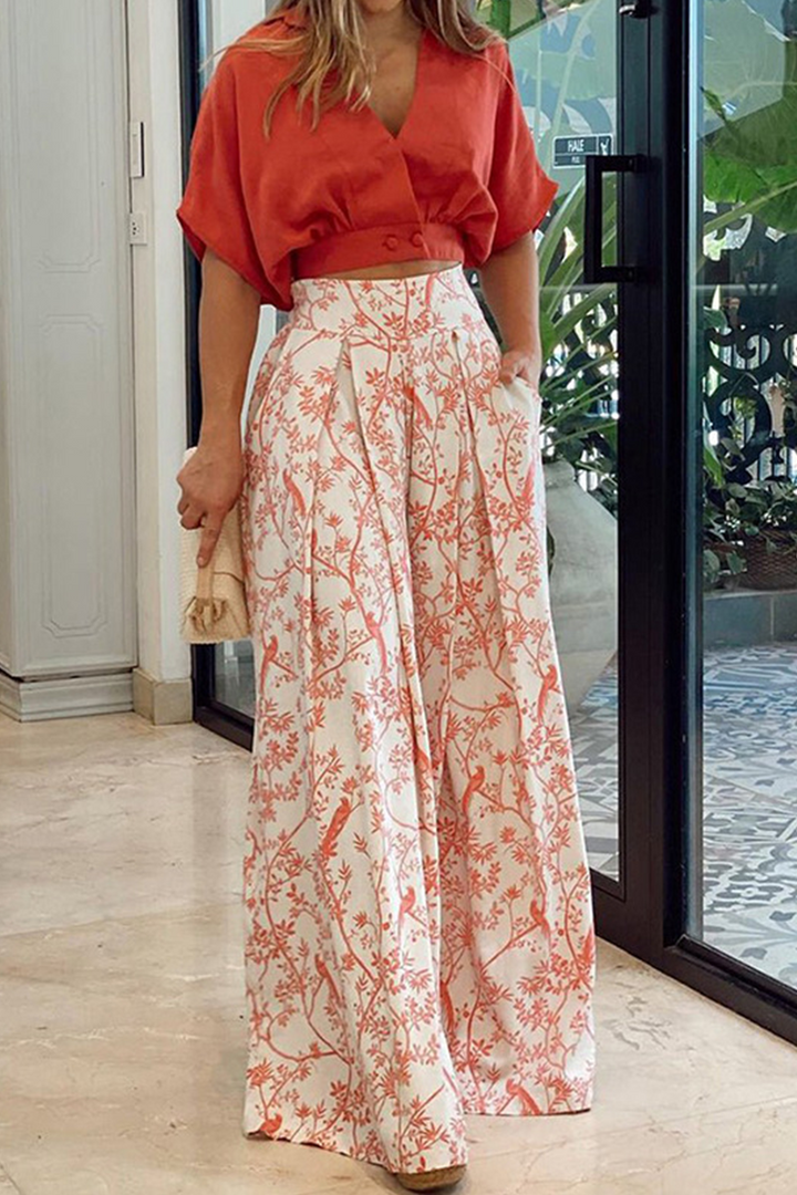 Set Kaïna pour femme, composé d'un haut court orange à manches bouffantes et d'un pantalon large à imprimé floral rouge et blanc, parfait pour un look élégant et moderne.