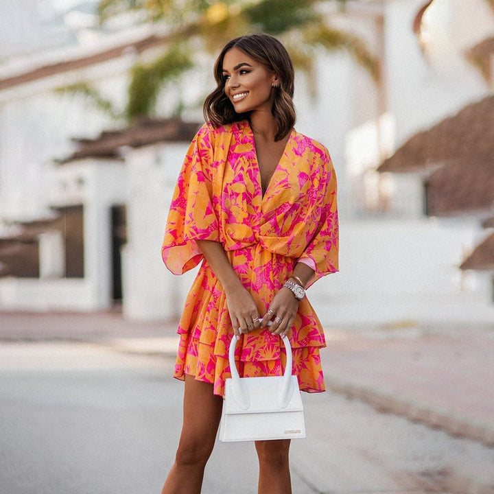 Robe mini florale pour femme, avec un motif floral vif en rose et jaune, manches larges et volants, idéale pour un look moderne et dynamique.
