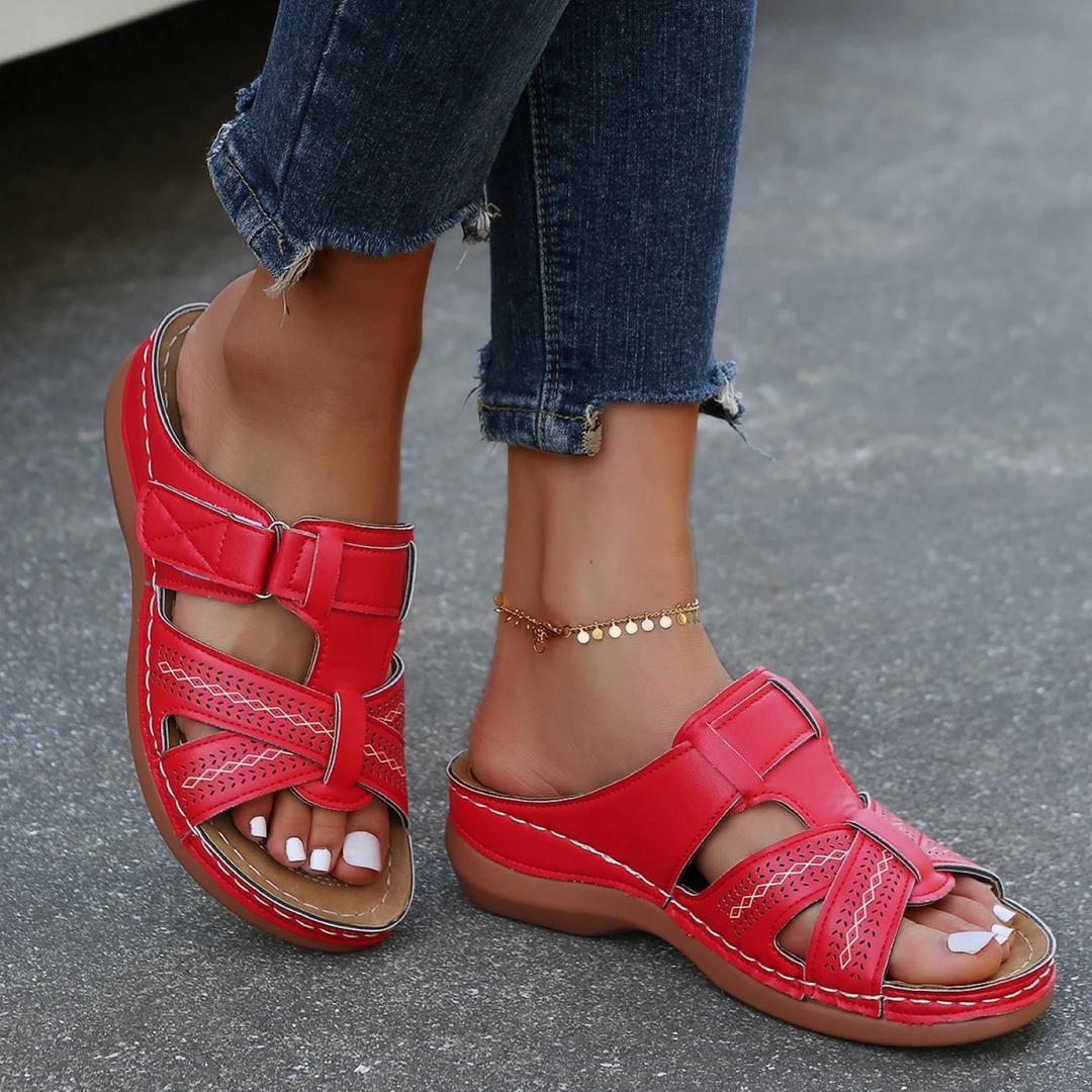Sandales femme rouges type mules avec brides ajourées et fermeture à scratch, semelle plate marron confortable, look estival décontracté.